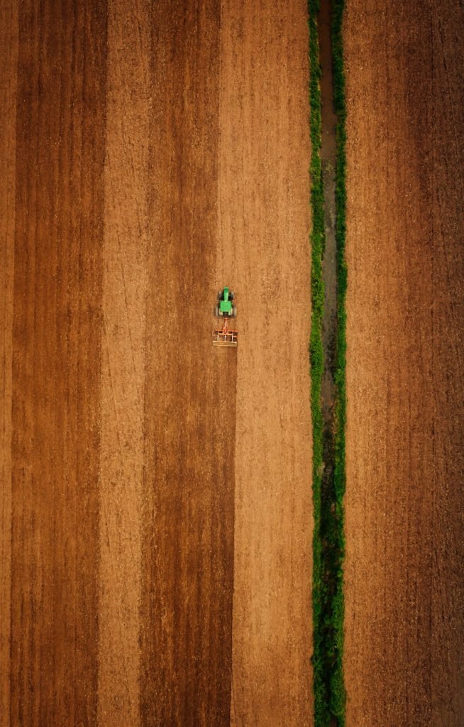 an-aerial-view-of-a-plowed-field-with-a-tractor-d1eqmq7ymac